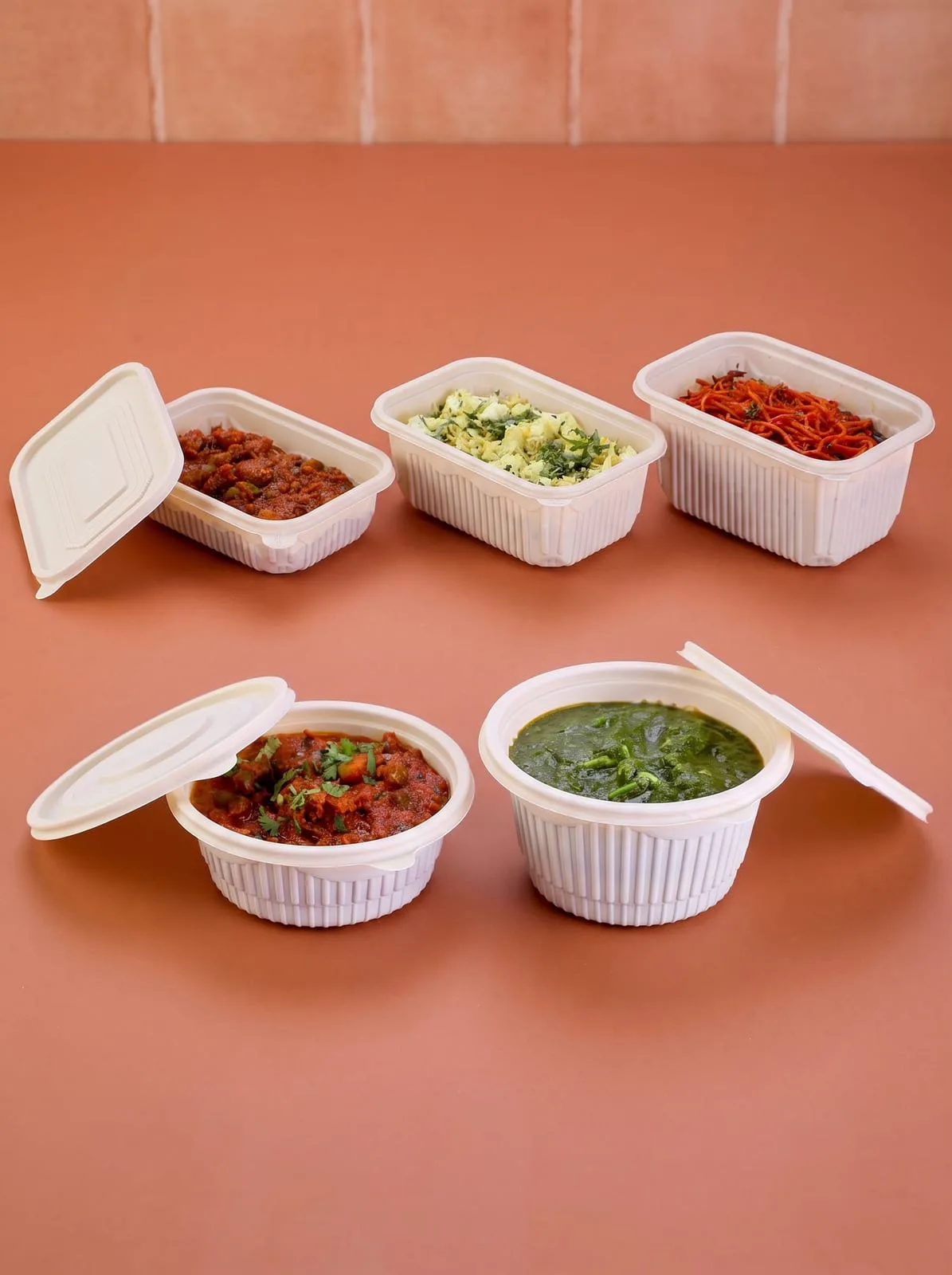 Oracle Group Eco Tray cornstarch round and rectangular containers with lids, holding curries